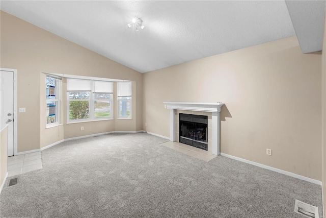 unfurnished living room with a tile fireplace, light carpet, and lofted ceiling