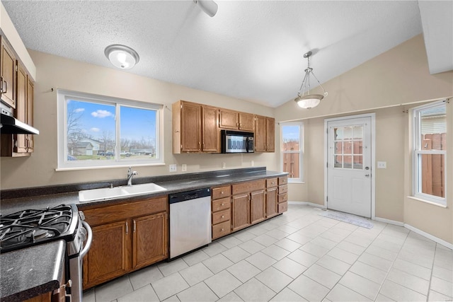 kitchen featuring pendant lighting, lofted ceiling, sink, light tile patterned floors, and stainless steel appliances