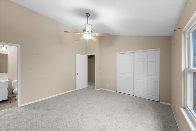 unfurnished bedroom featuring ceiling fan, a closet, ensuite bathroom, and vaulted ceiling