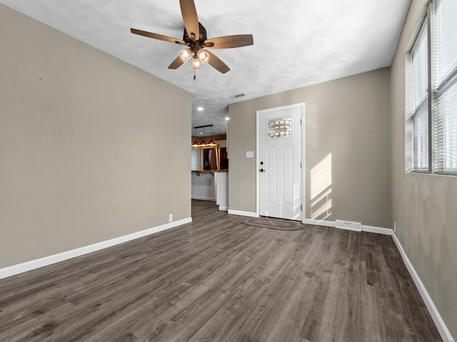 unfurnished living room with dark wood-type flooring and ceiling fan