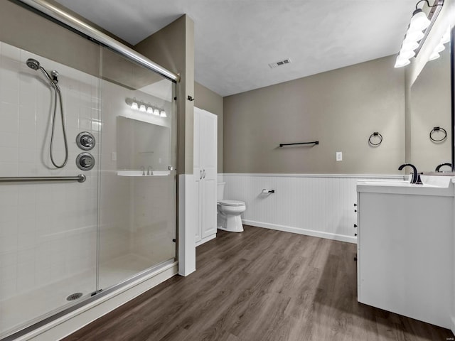 bathroom with hardwood / wood-style flooring, vanity, toilet, and a shower with shower door