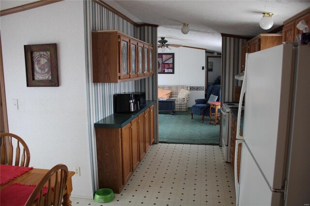 kitchen featuring vaulted ceiling, ceiling fan, white fridge, and a textured ceiling