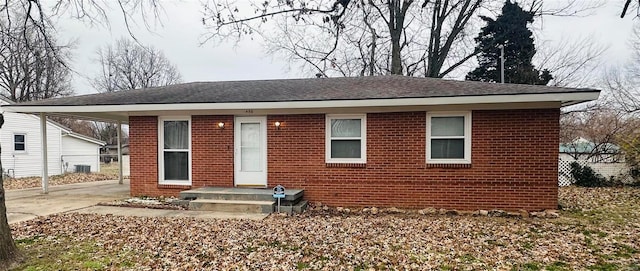 bungalow-style home featuring brick siding, concrete driveway, central AC, and roof with shingles