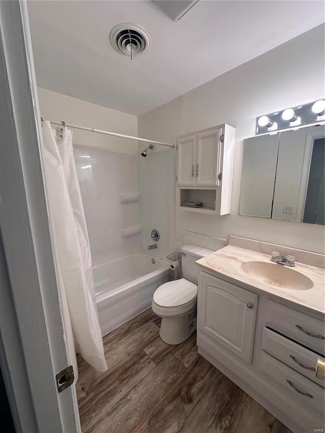 bathroom with vanity, wood finished floors, visible vents, shower / bath combo with shower curtain, and toilet