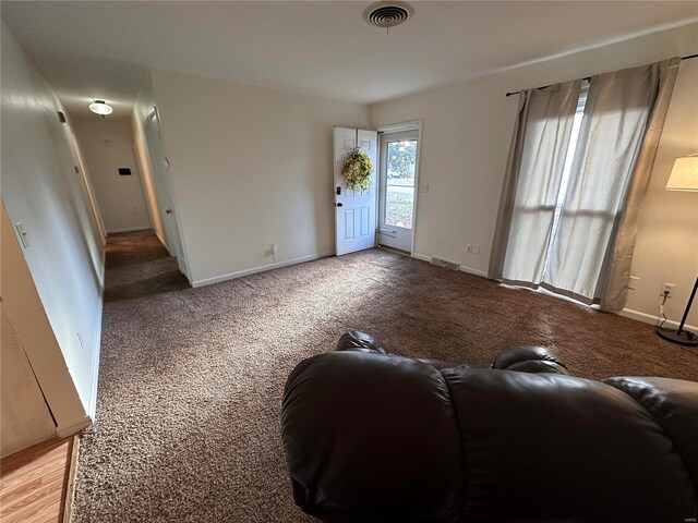 living area with visible vents, baseboards, and light colored carpet