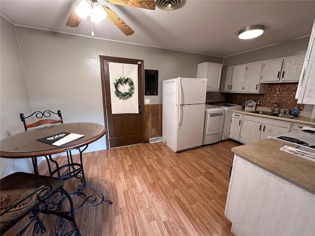 kitchen with a ceiling fan, a sink, freestanding refrigerator, white cabinets, and light wood finished floors