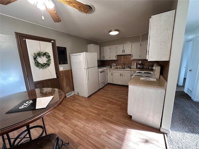 kitchen with light wood finished floors, a sink, washer / clothes dryer, white appliances, and light countertops