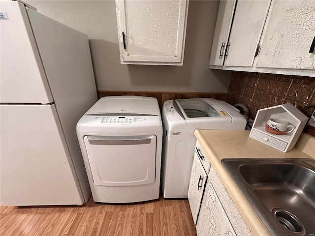 laundry room with light wood finished floors, washer / dryer, and a sink