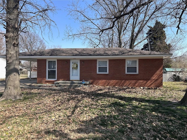 single story home with an attached carport, brick siding, and a front lawn