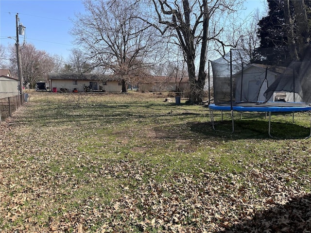 view of yard with a shed, an outdoor structure, a trampoline, and fence