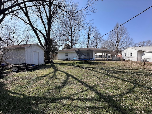 view of yard featuring a storage shed, an outdoor structure, a trampoline, and fence