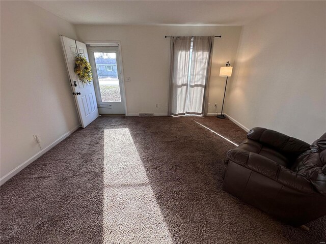 unfurnished living room featuring baseboards and carpet floors