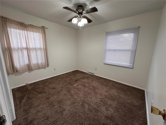 spare room featuring visible vents, baseboards, a ceiling fan, and dark carpet