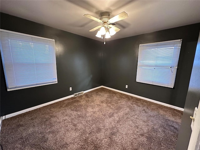 carpeted empty room with visible vents, a ceiling fan, and baseboards