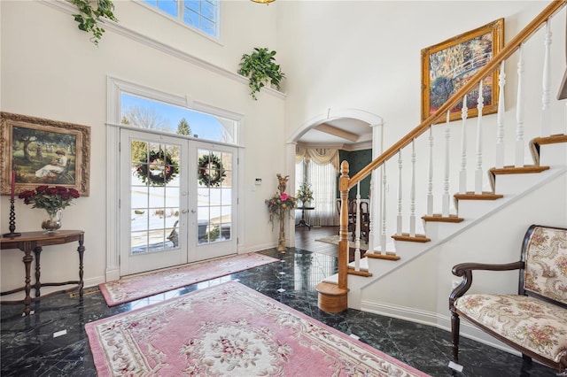 entrance foyer with a wealth of natural light, arched walkways, marble finish floor, and baseboards