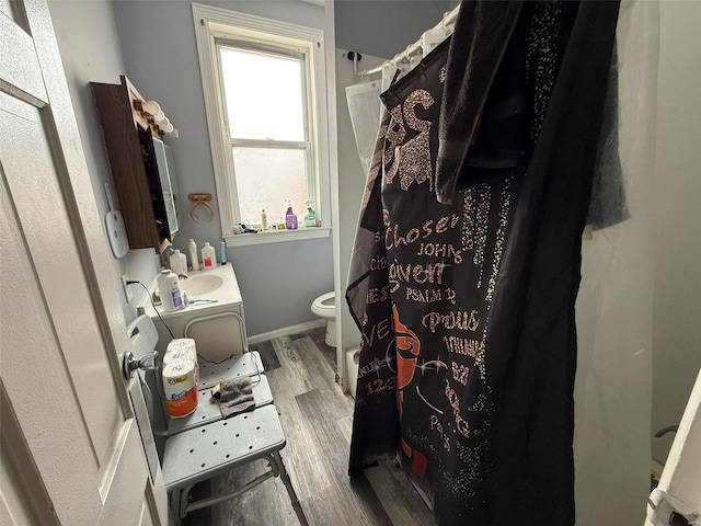 bathroom featuring wood-type flooring, vanity, toilet, and a wealth of natural light