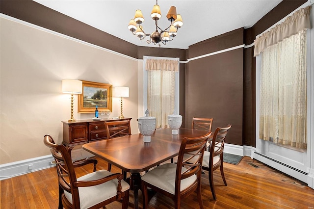 dining room with hardwood / wood-style flooring, a baseboard radiator, and a chandelier