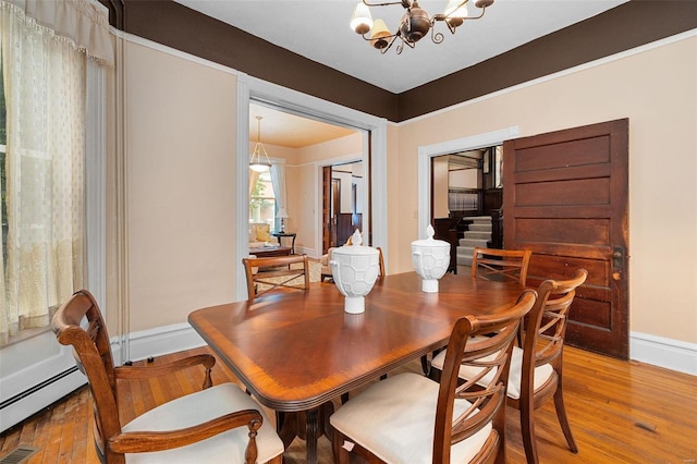 dining area featuring wood-type flooring, an inviting chandelier, and baseboard heating