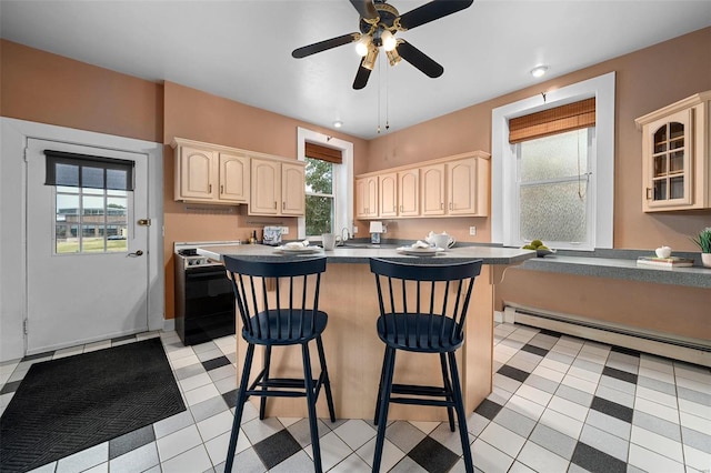 kitchen with a baseboard heating unit, electric range, ceiling fan, light tile patterned floors, and a kitchen bar