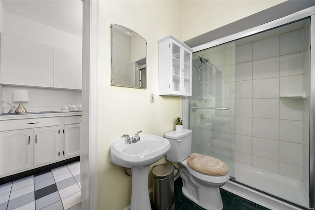 bathroom featuring tile patterned flooring, toilet, a shower with shower door, and sink