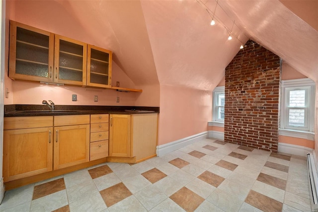 kitchen featuring sink, baseboard heating, brick wall, track lighting, and lofted ceiling