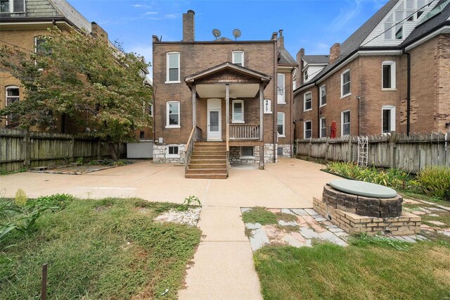 rear view of property featuring an outdoor fire pit