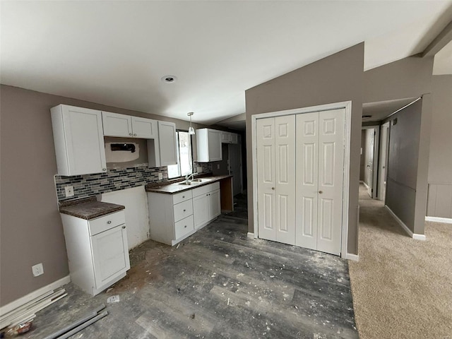 kitchen with decorative backsplash, sink, pendant lighting, white cabinets, and lofted ceiling