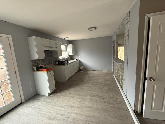 kitchen featuring white cabinets, light wood-type flooring, and tasteful backsplash