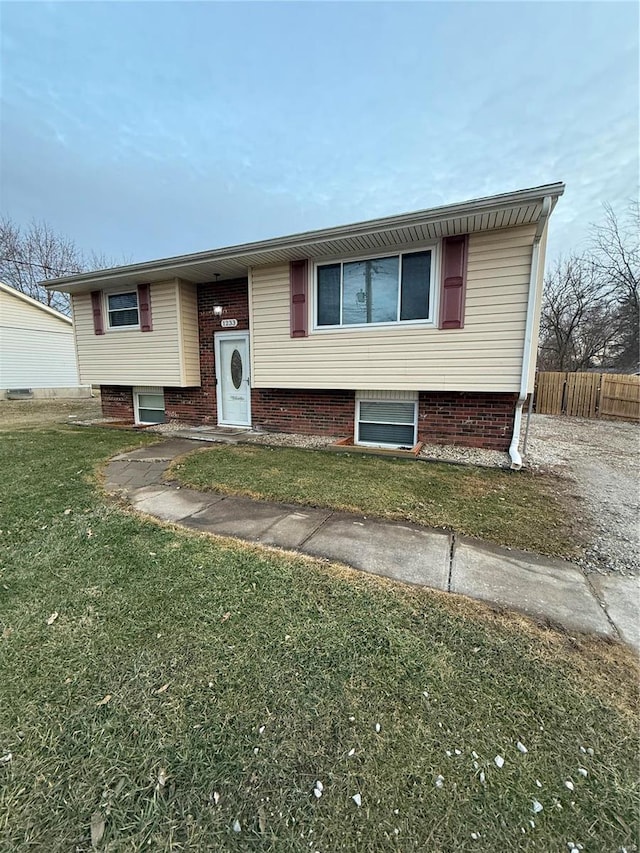 raised ranch featuring a front lawn and fence