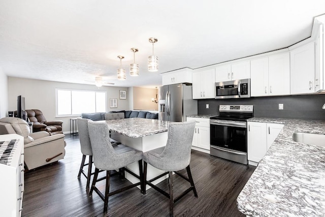 kitchen featuring a kitchen breakfast bar, dark wood-style floors, open floor plan, and stainless steel appliances