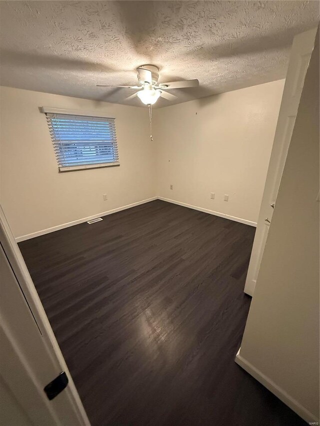 unfurnished room featuring a textured ceiling, a ceiling fan, dark wood-style flooring, and baseboards