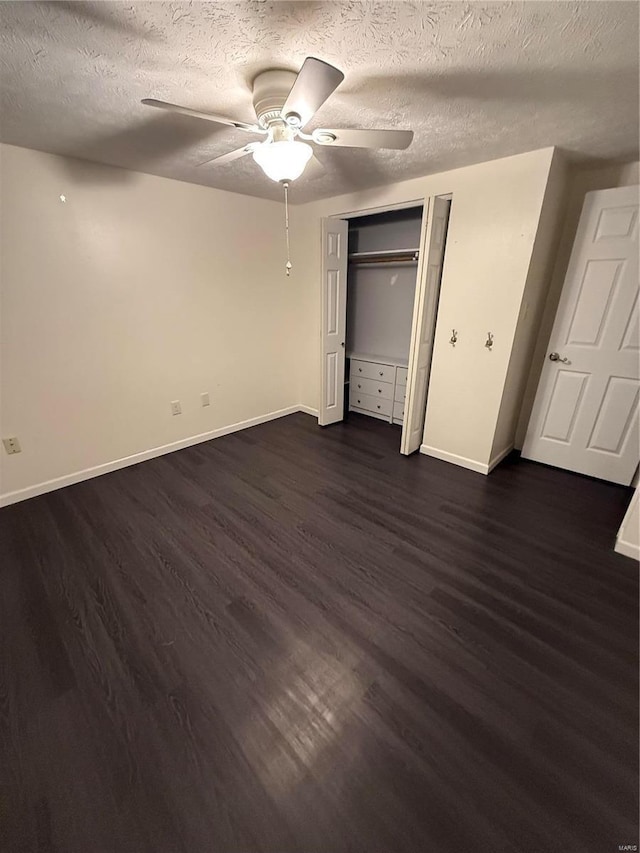 unfurnished bedroom featuring a ceiling fan, baseboards, dark wood finished floors, a closet, and a textured ceiling