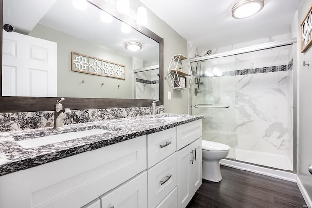 full bathroom featuring toilet, a sink, wood finished floors, a marble finish shower, and double vanity