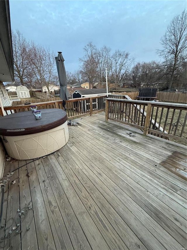 wooden terrace with a fenced backyard and a trampoline