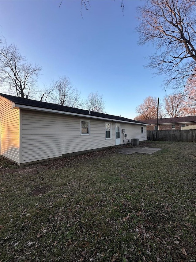 rear view of house featuring cooling unit, a patio area, and a lawn