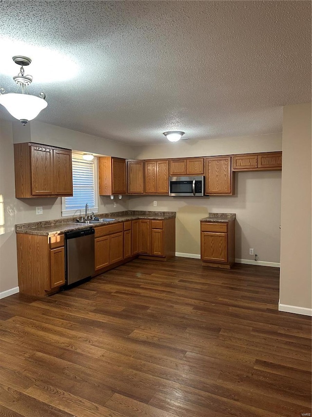 kitchen with dark wood-type flooring, sink, stainless steel appliances, and a textured ceiling