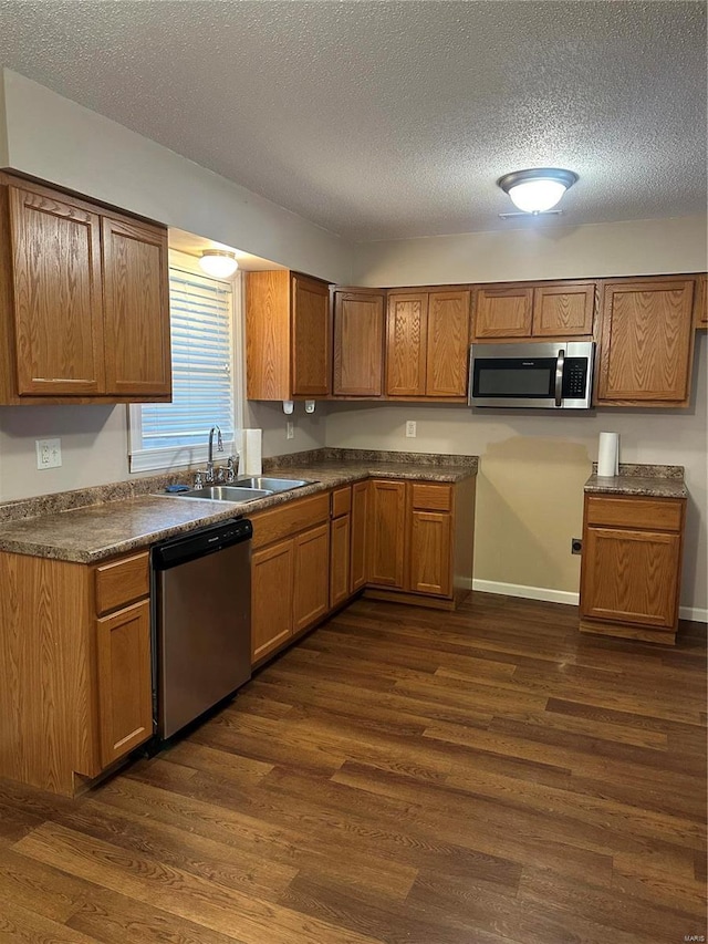 kitchen with dark hardwood / wood-style floors, sink, stainless steel appliances, and a textured ceiling