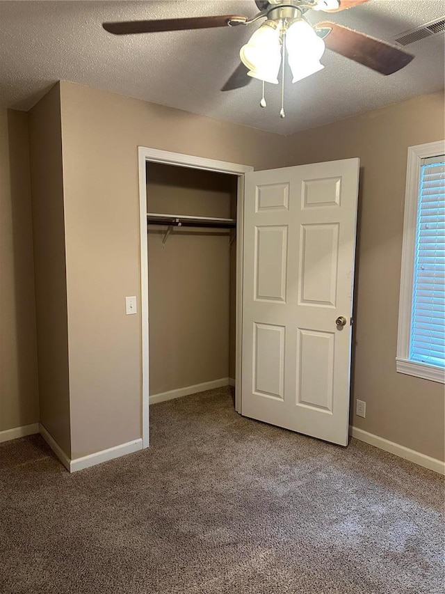 unfurnished bedroom featuring carpet flooring, a textured ceiling, a closet, and ceiling fan