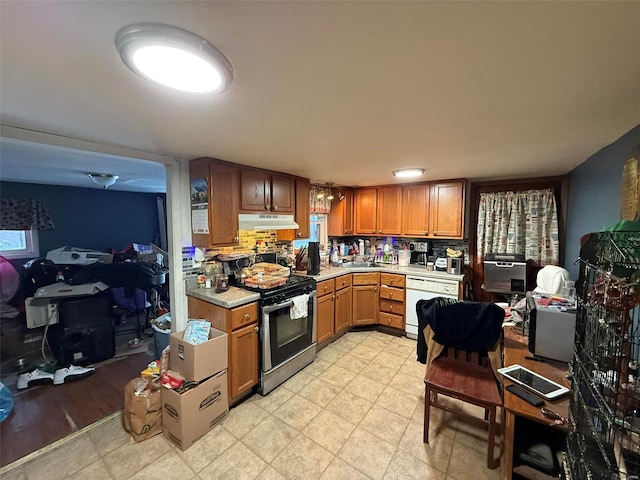 kitchen featuring white dishwasher, backsplash, gas stove, and sink