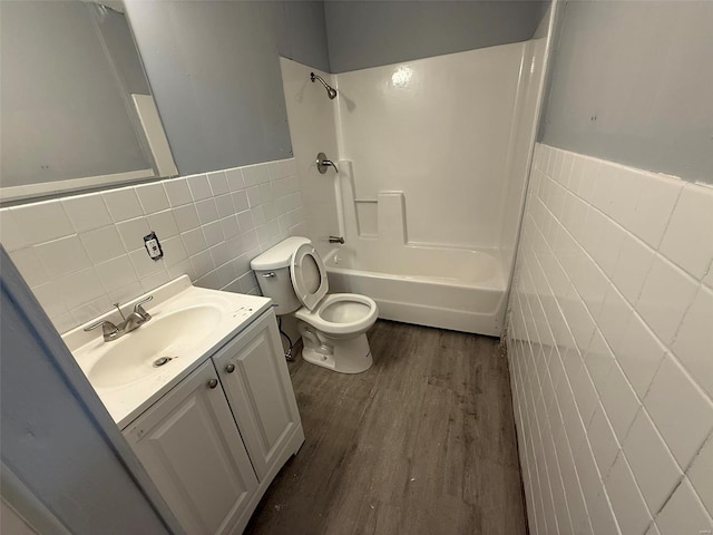 full bathroom with shower / tub combination, vanity, wood-type flooring, and tile walls