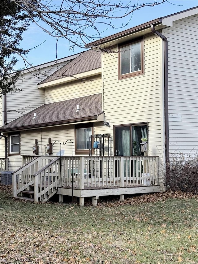 rear view of property with a lawn, a deck, and central AC