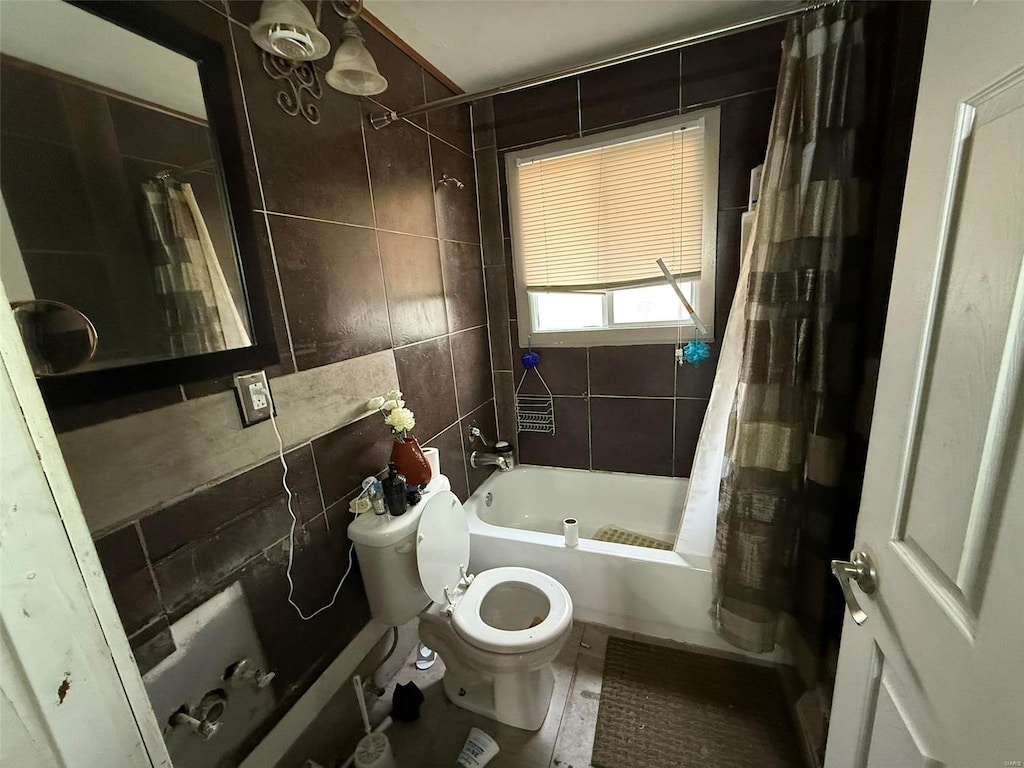 bathroom featuring tile patterned floors, toilet, shower / bathtub combination with curtain, and tile walls