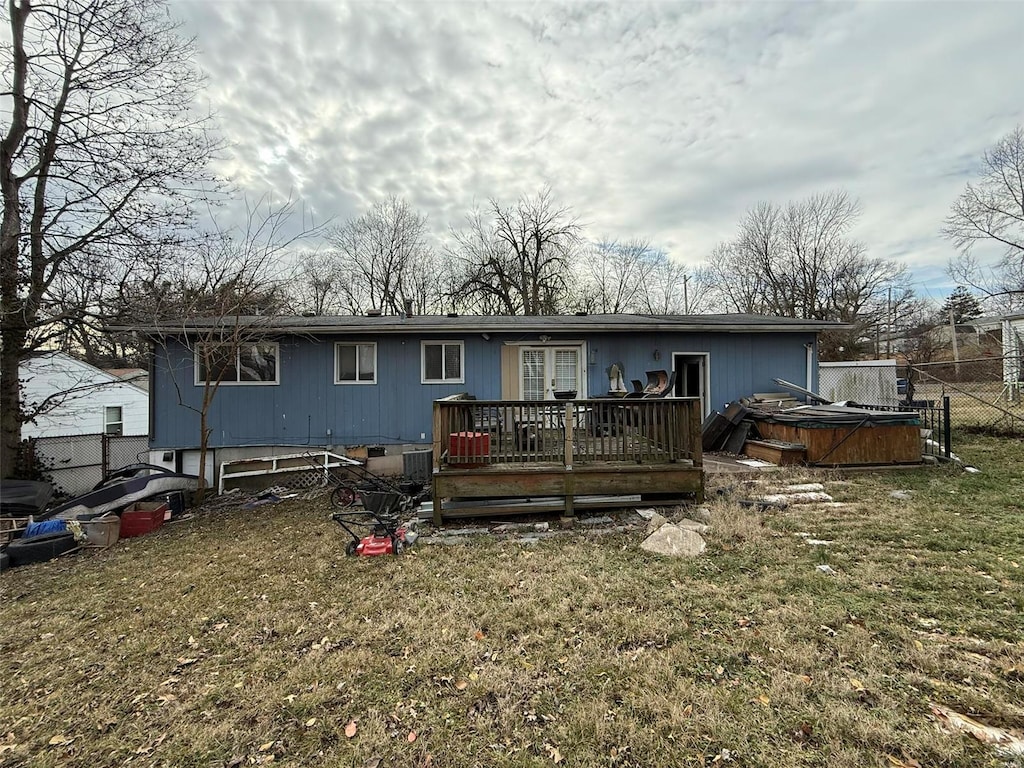 rear view of house with a lawn, a hot tub, and a deck