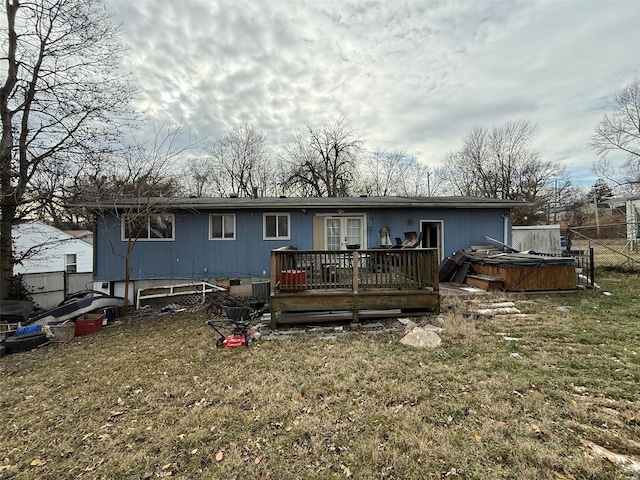 rear view of house with a lawn, a hot tub, and a deck