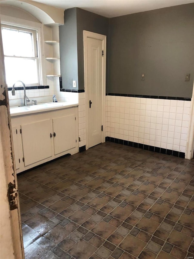 kitchen featuring white cabinets, sink, and tile walls