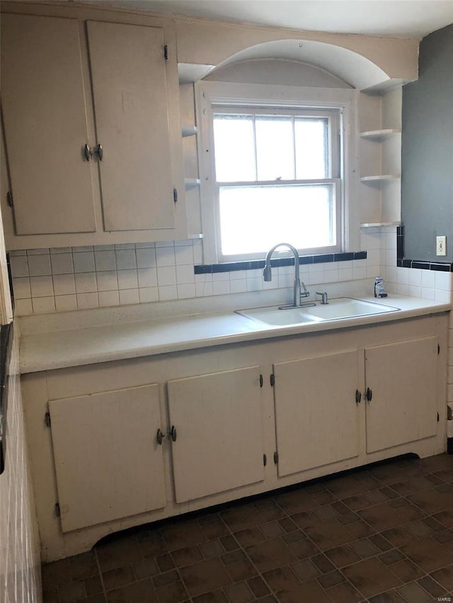 kitchen featuring decorative backsplash, sink, and white cabinets