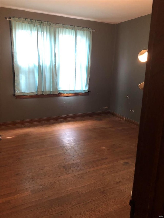 spare room featuring dark hardwood / wood-style flooring and plenty of natural light