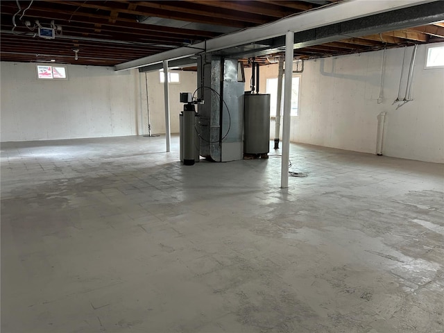 basement featuring heating unit, a healthy amount of sunlight, and gas water heater