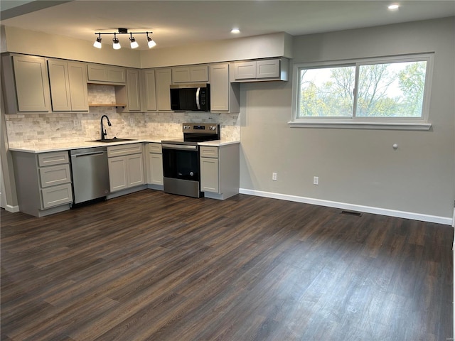 kitchen featuring decorative backsplash, stainless steel appliances, sink, gray cabinets, and dark hardwood / wood-style floors