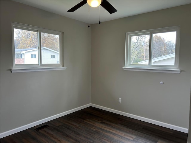 spare room featuring a wealth of natural light, dark wood-type flooring, and ceiling fan